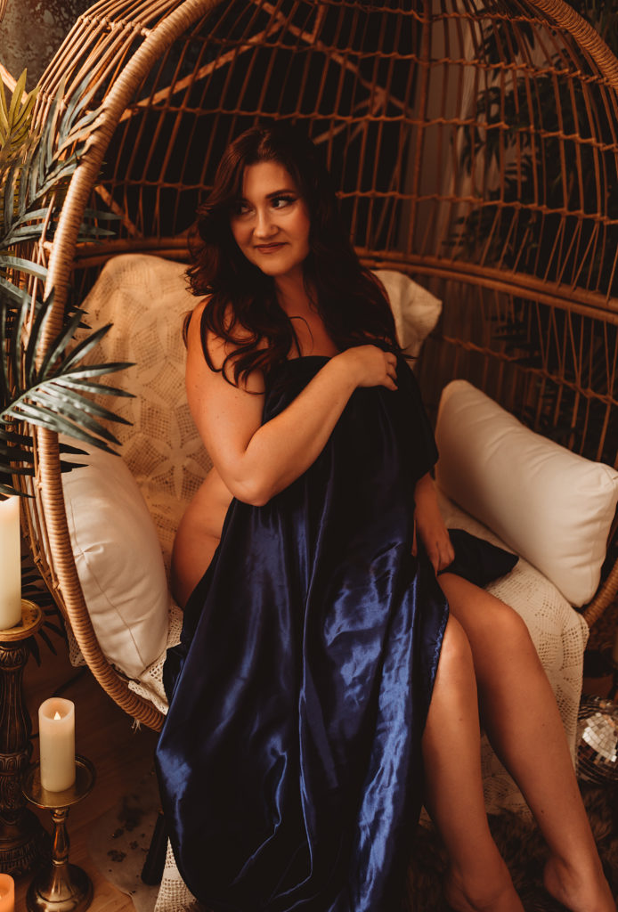 Rocklin boudoir session in egg chair with satin sheet and cozy, feminine energy
